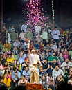 Priest throwing flower petals during Ganga aarti on banks of holy river Ganges in one of the oldest living cities of World and