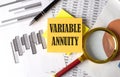 VARIABLE ANNUITY text on a sticky on the graph background with pen and magnifier