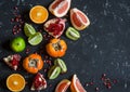 Variation of fresh fruit - grapefruit, persimmon, kiwi, pomegranate, orange, lime. On the dark background