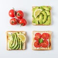 Variation of healthy breakfast toasts with avocado and cherry tomatoes on white background.