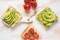 Variation of healthy breakfast toasts with avocado and cherry tomatoes on white wooden background. Food concept