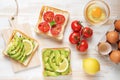 Variation of healthy breakfast toasts with avocado and cherry tomatoes on white wooden background. Food concept