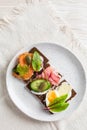 Variation of healthy open sandwiches on Pumpernickel bread with vegetables, salmon, ham, herbs and soft cheese Royalty Free Stock Photo