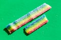 Varicoloured marmalade in the sugar on the green background. Natural rainbow colored long marmalade candy. Copy space