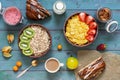 Varied healthy breakfast on a blue rustic background. Corn flakes, strawberries, muesli, kiwi, almonds, milk, berry mousse, baked Royalty Free Stock Photo