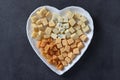 Varieties of elite cheese in a heart-shaped plate for Valentine's Day on dark gray background, Top view