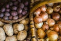 Varieties of raw potatoes and onions in baskets Royalty Free Stock Photo