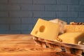 A variety of aged cheeses in a substrate on a wooden table against a brick wall Royalty Free Stock Photo