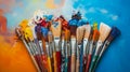 A variety of artist paint brushes laid out on a vibrant background, in art class extracurricular hobby at school or