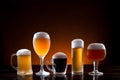 Variety of beers in different glasses on wooden base. Dark and orange background