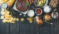 Variety of beers, sausages, burgers, potato, corn on dark background Royalty Free Stock Photo