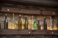 A variety of bottles stand on a wooden shelf against the background of a stone wall. Royalty Free Stock Photo