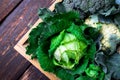 Variety of cabbages in wooden basket on brown background. Harvest. Top view. Royalty Free Stock Photo