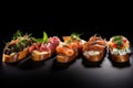 Variety of canapes on black background. Bruschetta with salmon, prosciutto, mozzarella cheese, tomato, pesto, basil.
