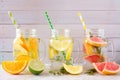 Variety of citrus infused detox water drinks in mason jars against wood