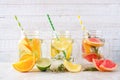 Variety of citrus infused water drinks in mason jars against white wood