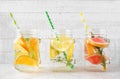 Variety of citrus infused water drinks in mason jars against white wood