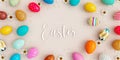 Variety of colored eggs with white flowers decoration and Happy Easter text on beige background Royalty Free Stock Photo