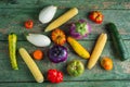 Variety of colorful red, green, yellow, white, tomatoes, zucchini, corn and eggplants over old green texture background
