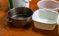 Variety of containers arranged on the wooden floor of house. To accommodate rainwater leaking from the roof while in heavy rain