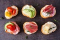 Variety of cream cheese crostini appetizers with a selection of toppings against a dark stone background Royalty Free Stock Photo