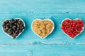 Variety of currant berries black, red and white in heart shape bowls on blue wooden background. summer food concept Royalty Free Stock Photo