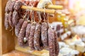 Variety of delicious dried sausages hanged on wooden rack at local farmer market. Fresh tasty meat delicatessen at butcher store