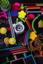 Variety of different bright colorful school supplies on black background. Clock, paperclios, pencil, pen, sticker, flower.