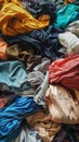 A variety of different colored clothes piled on top of each other, creating a stack of laundry. The clothes appear to be