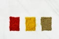 Variety of different ground spices in powder peppers paprika turmeric laid out in color sample boxes on white marble stone