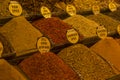 A variety of different yellow, red and orange piles of herbs and spices with names on sale on a shelf on the bazaar market of Royalty Free Stock Photo