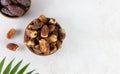 Variety of dried dates fruits in a wooden bowl on a white background.