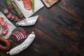 Variety of dry cured chorizo, fuet and other sausages cut in slices with herbs on old wooden table, top view with copy space