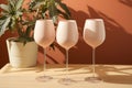 Variety of empty glasses on peach background with trendy hard shadows and sun light. Peach fuzz pantone color of year 2024.