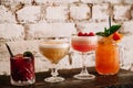 A variety of four alcoholic cocktails against white brick background