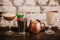 A variety of four alcoholic cocktails against white brick background