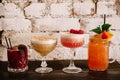 A variety of four alcoholic cocktails against white brick background