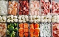 A variety of fresh, colorful vegetables arranged neatly in a transparent storage container, including broccoli, carrots