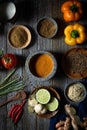 Variety of freshly-prepared vegetables and seasonings arranged in colourful bowls on a wooden table