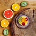 Variety of fruits grapefruit, oranges, kiwi, lemon, mint, cake, sweet fruit dessert on a plate on a wooden board, on the stump the