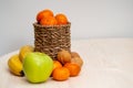 A variety of fruits and nuts on a wooden table. Tangerines in a wicker basket, bananas, apples and walnuts.