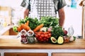 Variety of fruits and vegetables at home or kitchen restaurant with unrecognizable chef in background - concept of diet and