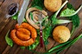 A variety of grilled sausages, sauce, fork, knife and corn bun on a wooden surface with greens: lettuce, dill and onion. Picnic - Royalty Free Stock Photo
