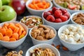 A variety of healthy snacks including nuts, fruits and vegetables in small white bowls on a grey background. Ai Royalty Free Stock Photo