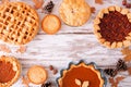 Variety of homemade fall pies, top down view frame on a white wood background