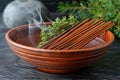 A variety of incense sticks in a ceramic bowl with smoke rising from them.