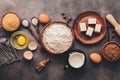 A variety of ingredients for baking, flour, butter, milk, eggs, cocoa powder, spices on a dark retro background. Top view, flat Royalty Free Stock Photo