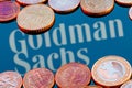 Variety of metal coins on background of Goldman Sachs bank logo