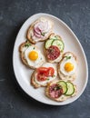 Variety of mini sandwiches with cream cheese, vegetables, quail eggs and salami. Sandwiches with cheese, cucumber, radish, tomatoe