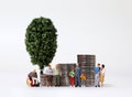 A variety of miniature people and pile of coins with miniature tree. Royalty Free Stock Photo